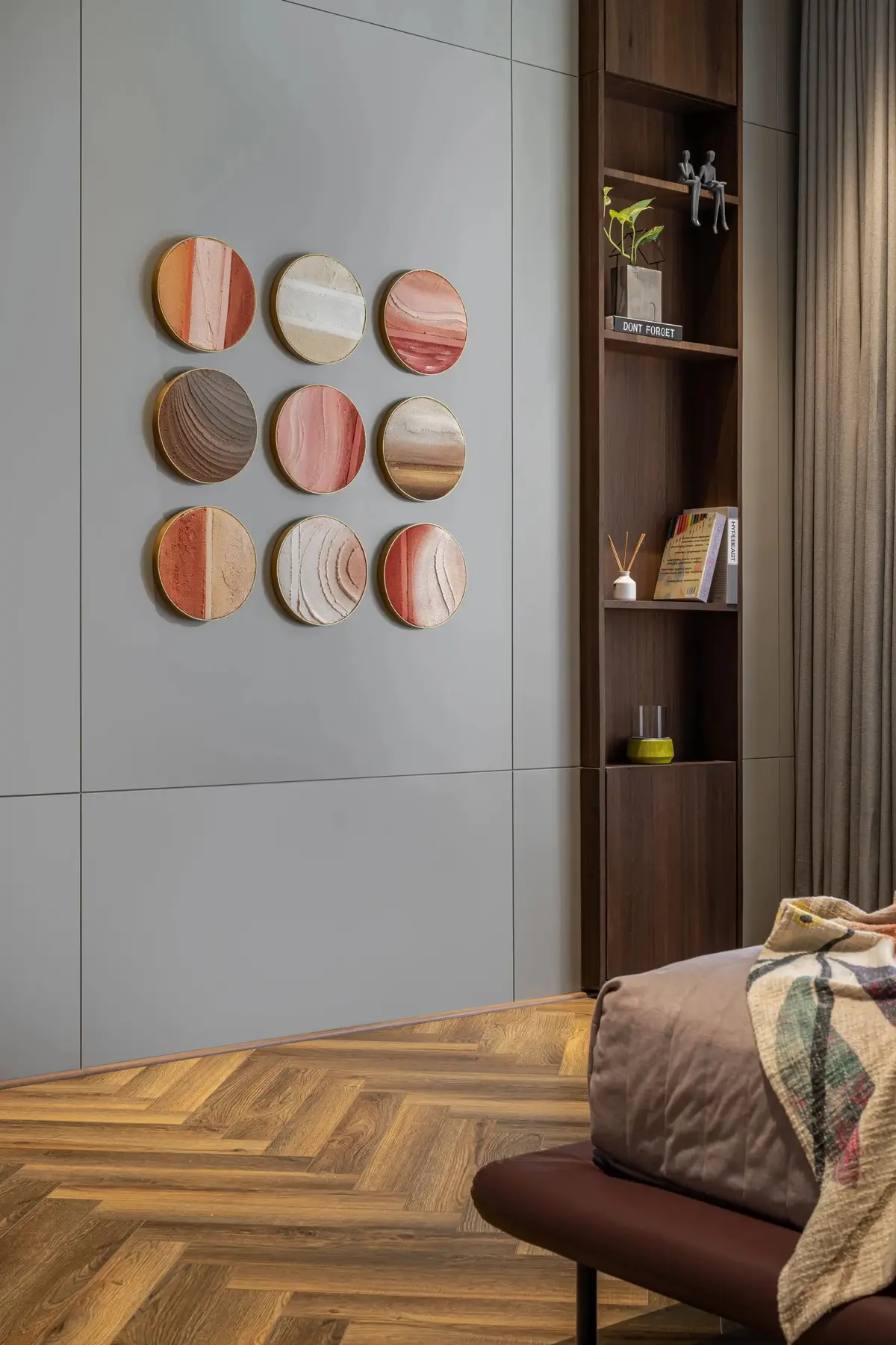 Bedroom wall with circular textured artworks above a herringbone timber floor