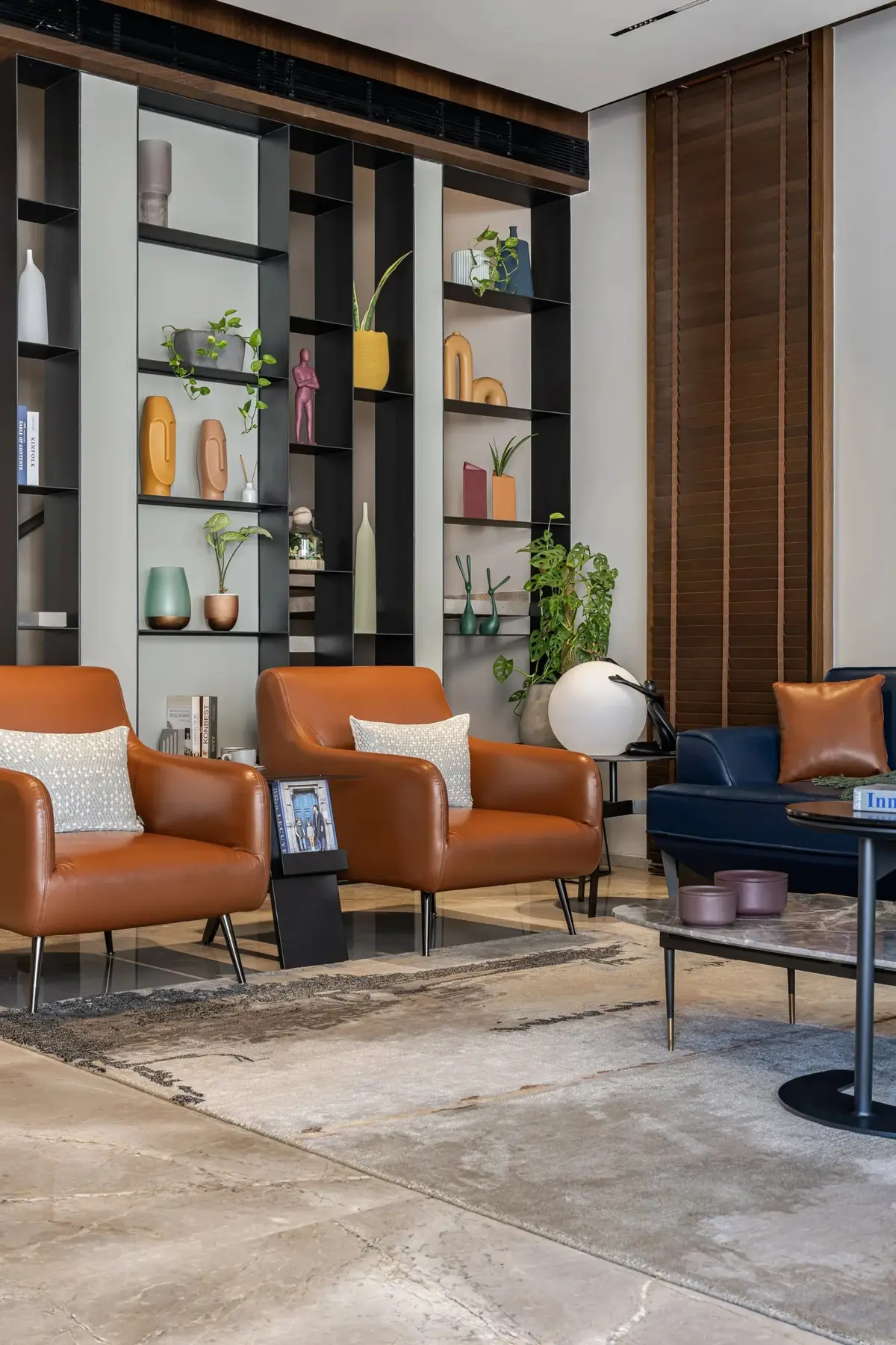 Display shelving behind orange leather armchairs in the living area
